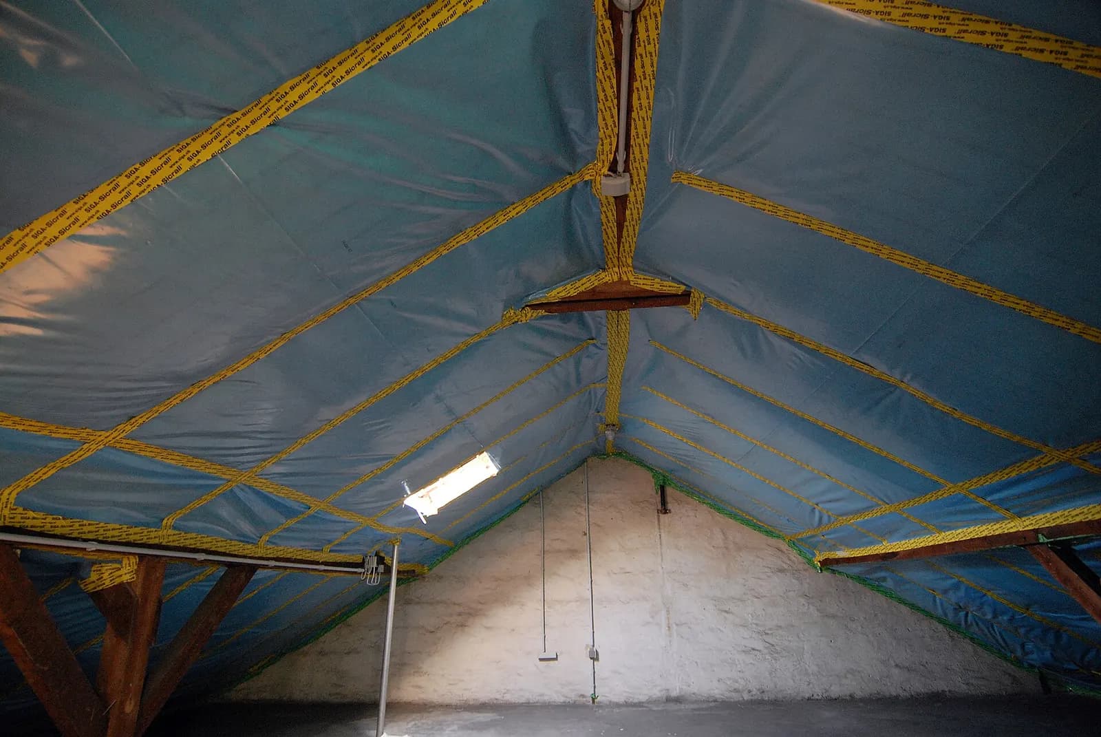 Illustration : combles en cours de rénovation, membrane bleue tendue sous les chevrons
