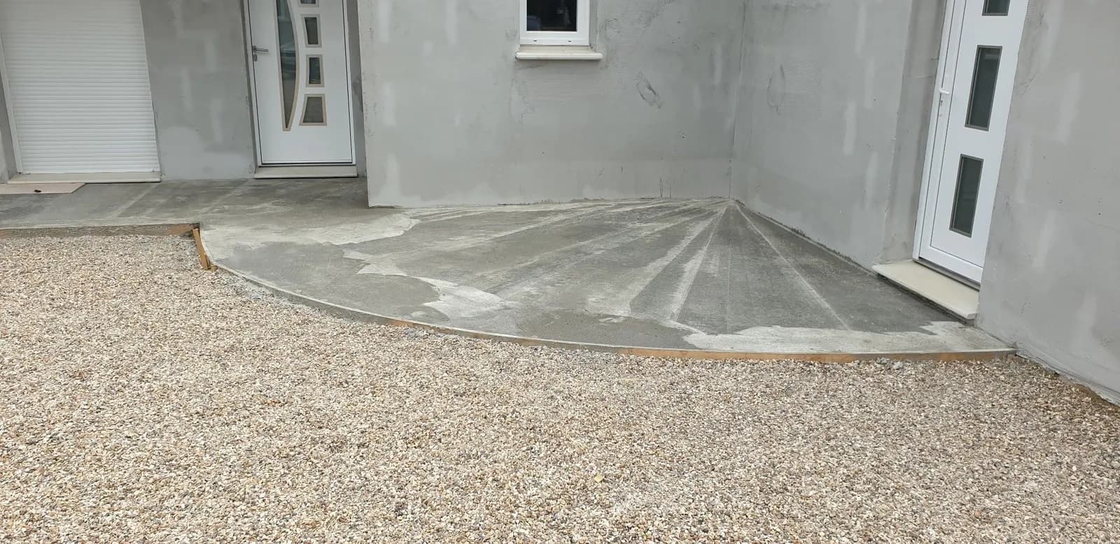 Dalle béton coulée par Bouthors Couverture devant l’entrée d’une maison neuve, gravier autour
