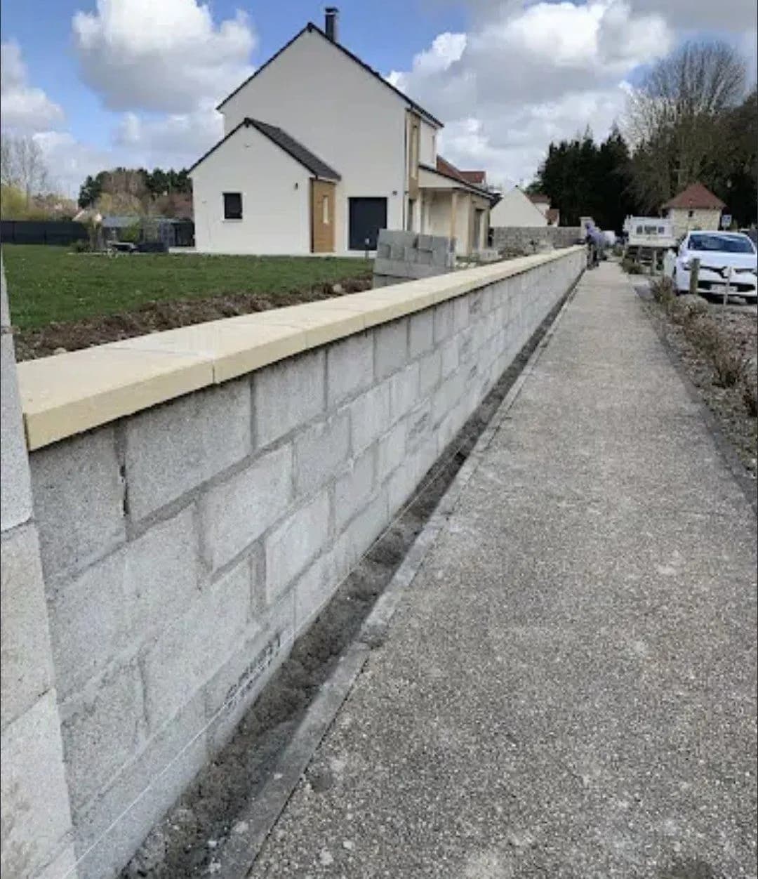 Mur en blocs béton coiffé d’un chaperon clair le long d’une allée, monté par Bouthors Couverture