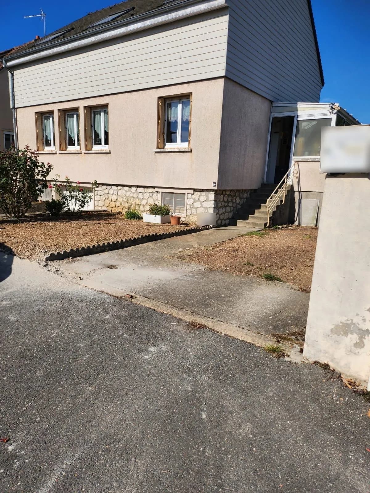 Cour d’entrée en gravier et béton fissuré devant une maison, avant les travaux, chantier de SJ Rénovation, partenaire de Bouthors Couverture