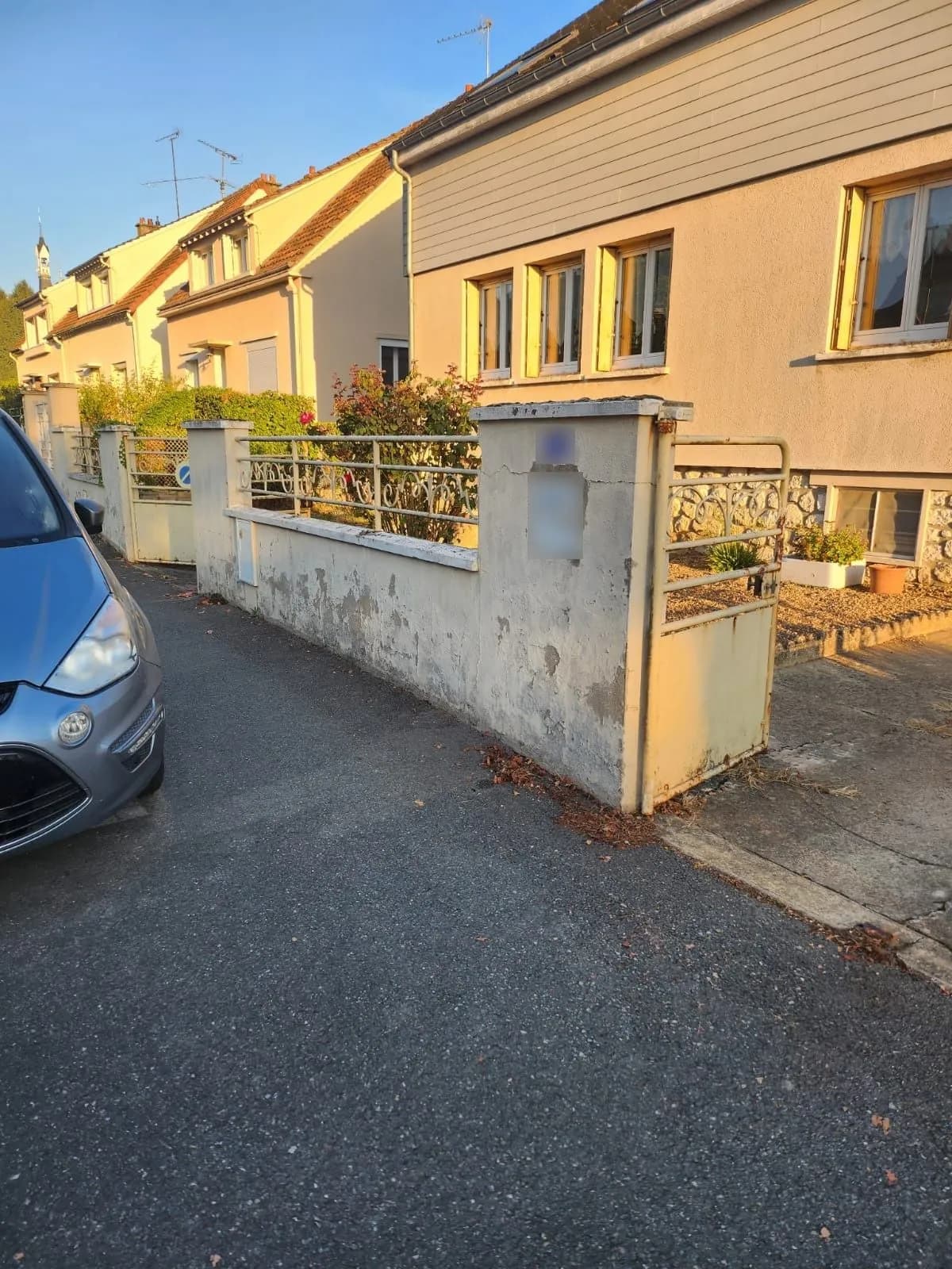 Mur de clôture sur rue à l’enduit écaillé et fissuré, piliers et grille, avant les travaux, chantier de SJ Rénovation, partenaire de Bouthors Couverture