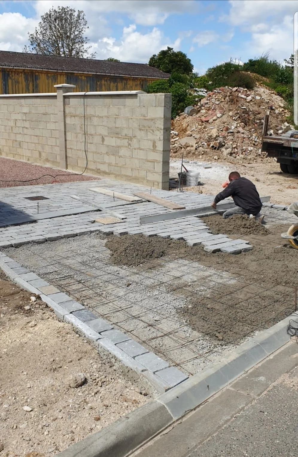 Pose de pavés gris en cour par Bouthors Couverture, devant un mur de clôture neuf