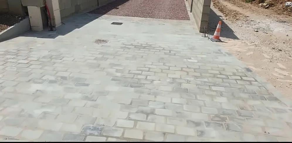 Entrée de propriété pavée de pavés gris par Bouthors Couverture, entre deux murs